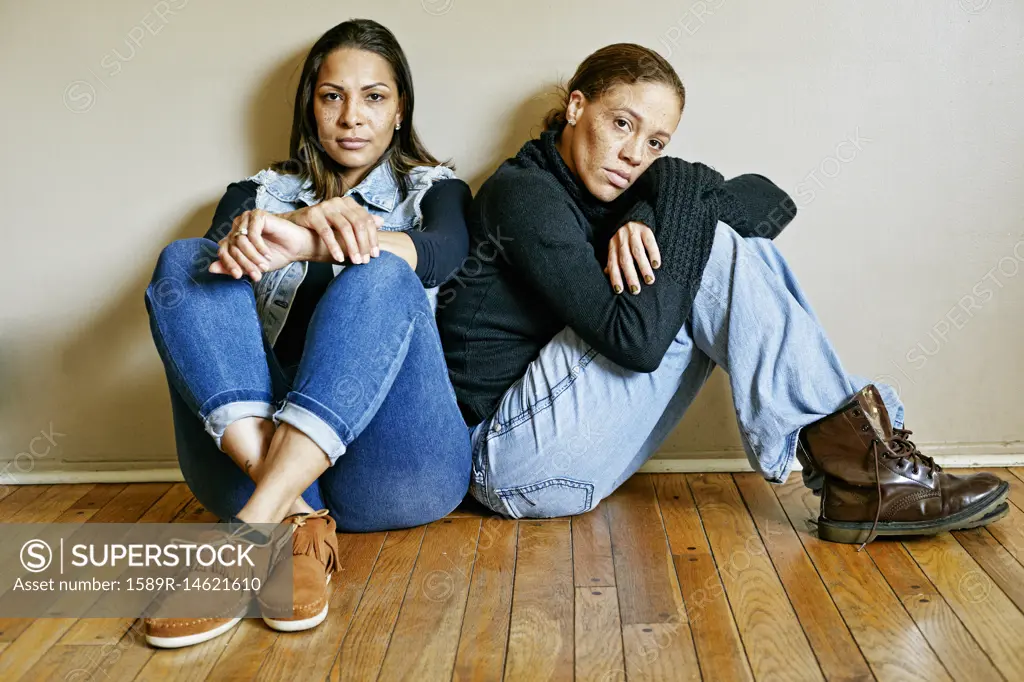 Serious mixed race women sitting on floor