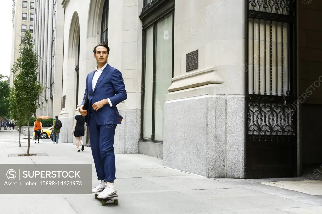 Caucasian businessman skateboarding on urban sidewalk