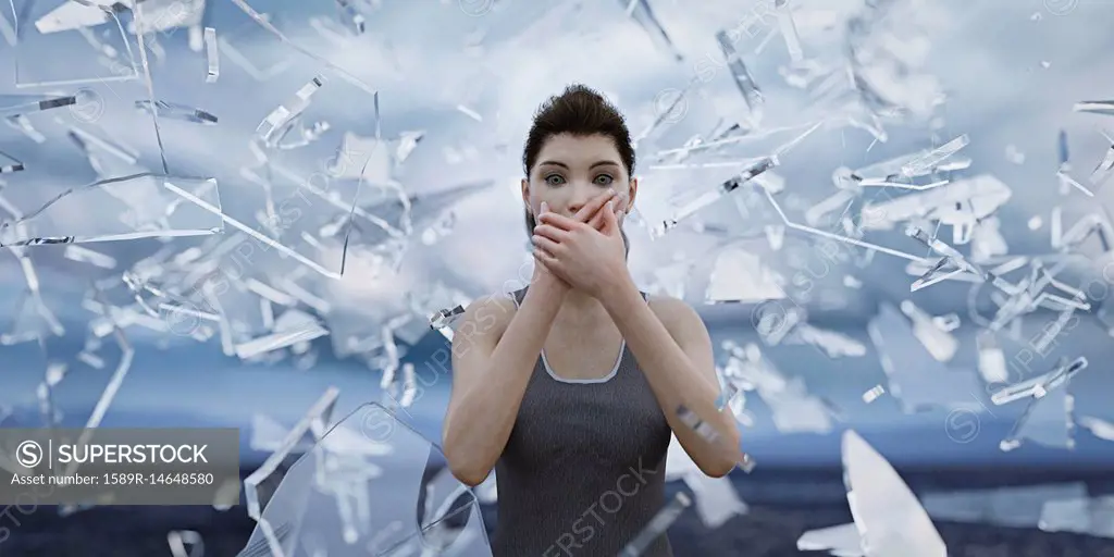 Shards of glass surrounding woman covering mouth with hands