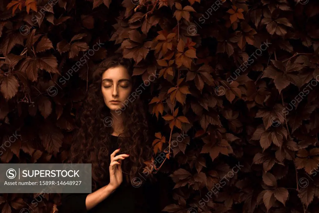 Serious Caucasian woman standing in autumn leaves