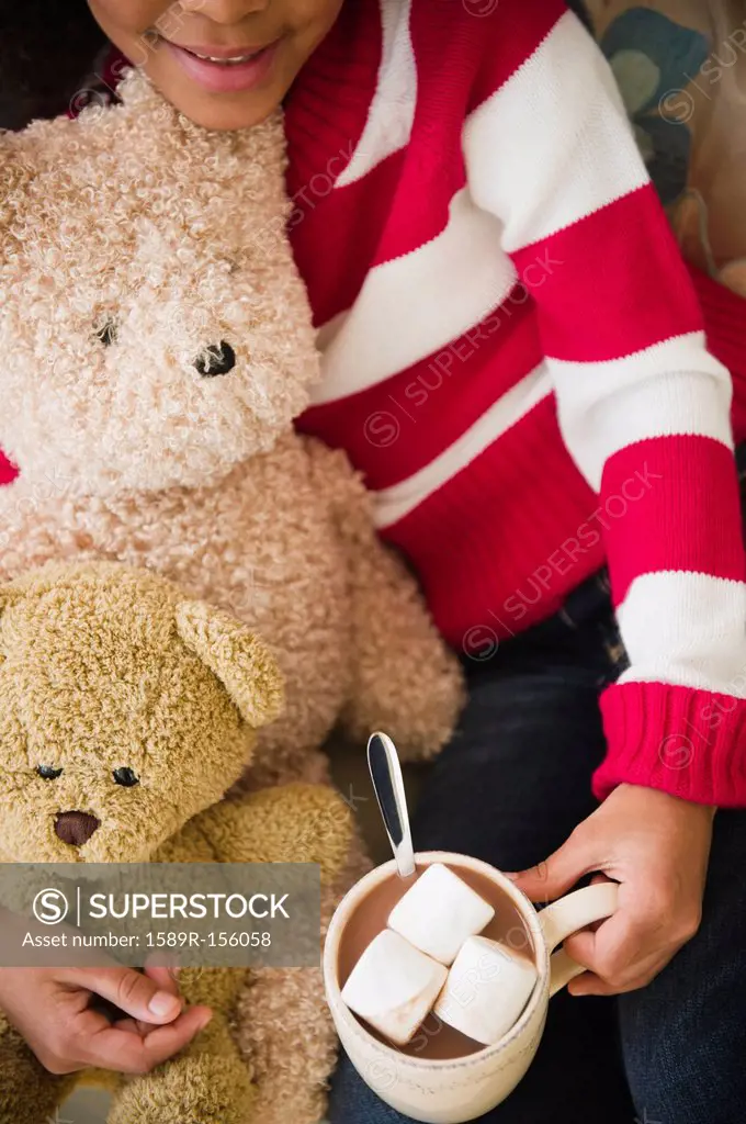 Mixed race girl with teddy bears drinking hot chocolate
