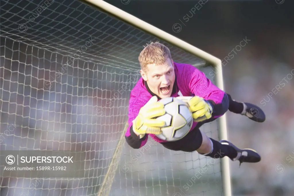 Male goalie catching ball in midair