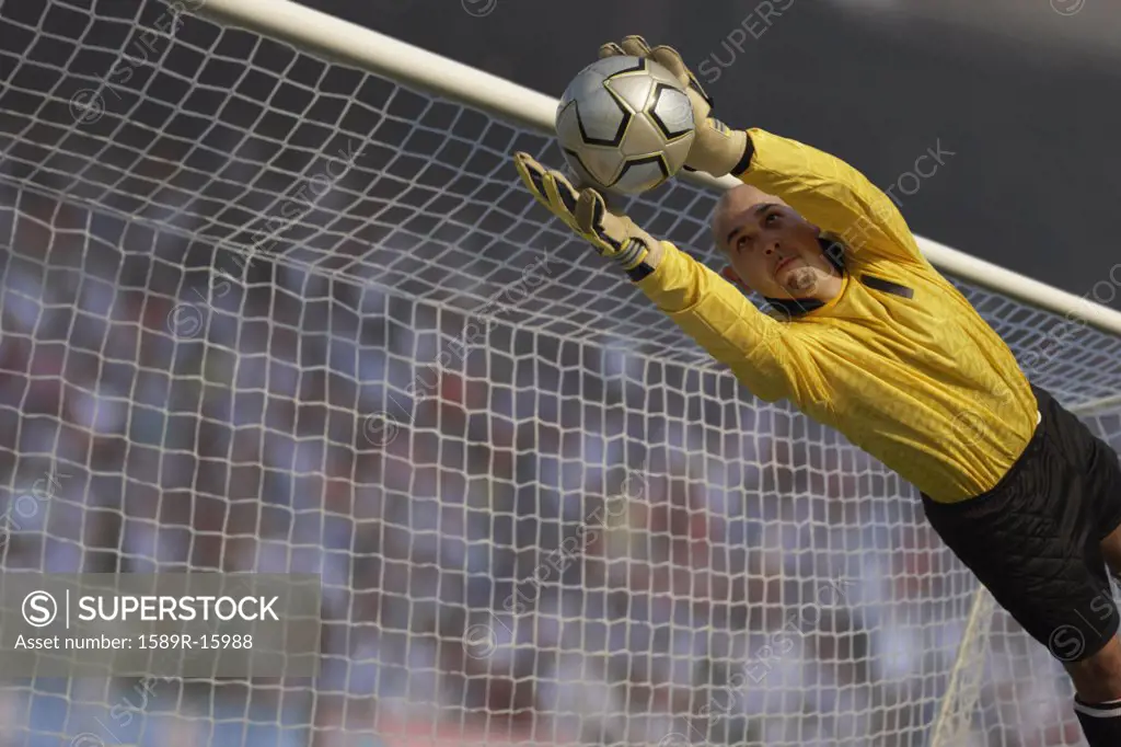 Male goalie catching ball in midair