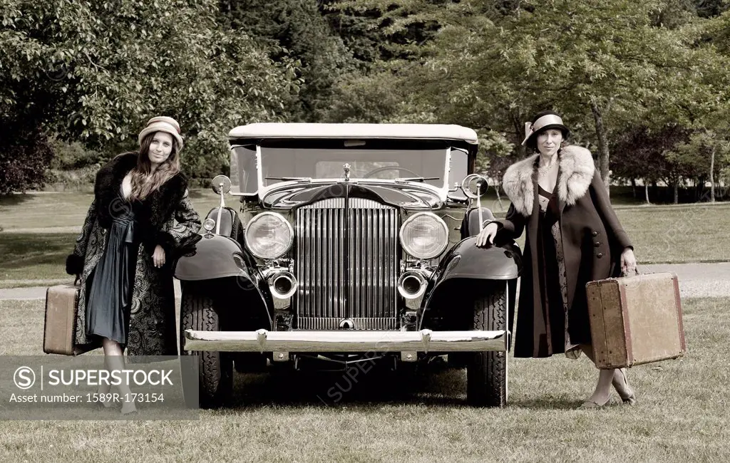 Caucasian women with luggage by vintage car