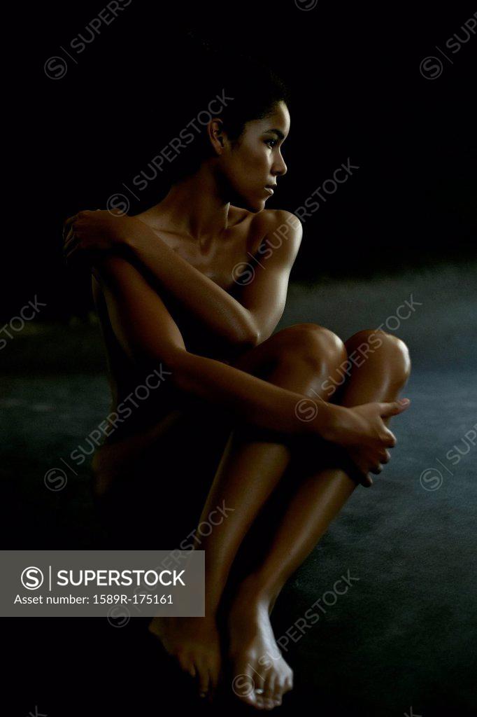 Naked woman in profile, sitting on floor - SuperStock