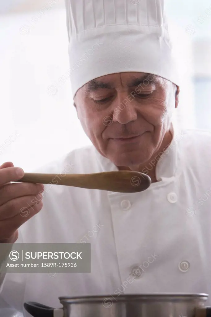 Hispanic chef tasting food in kitchen