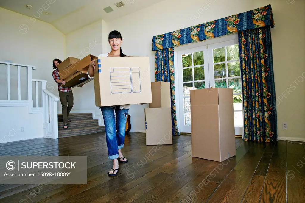 Couple carrying boxes in new home