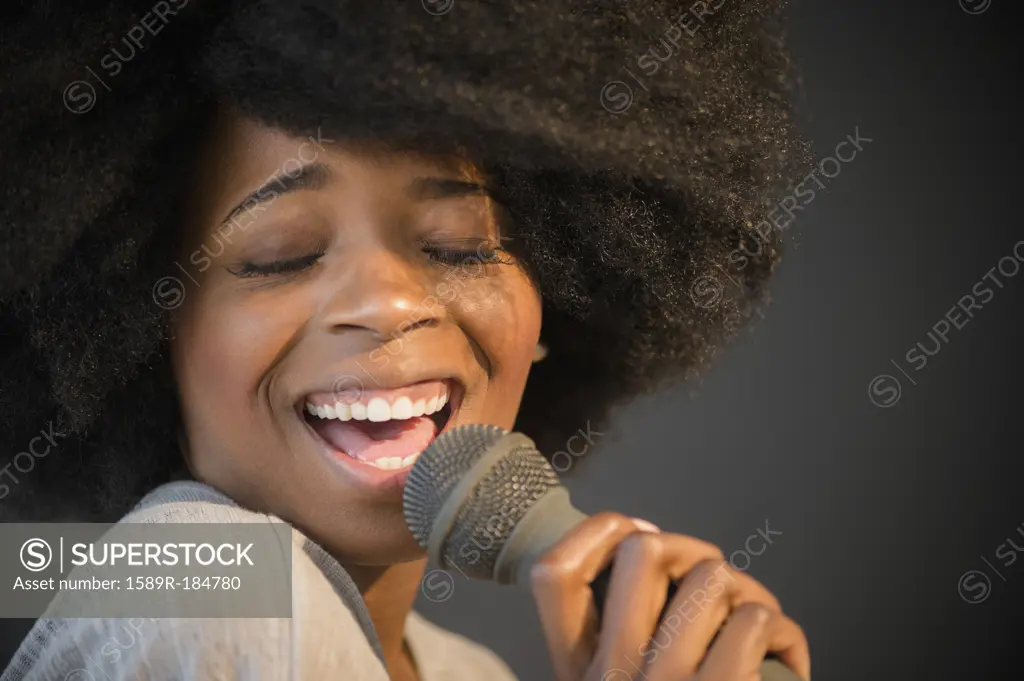 Mixed race woman singing into microphone