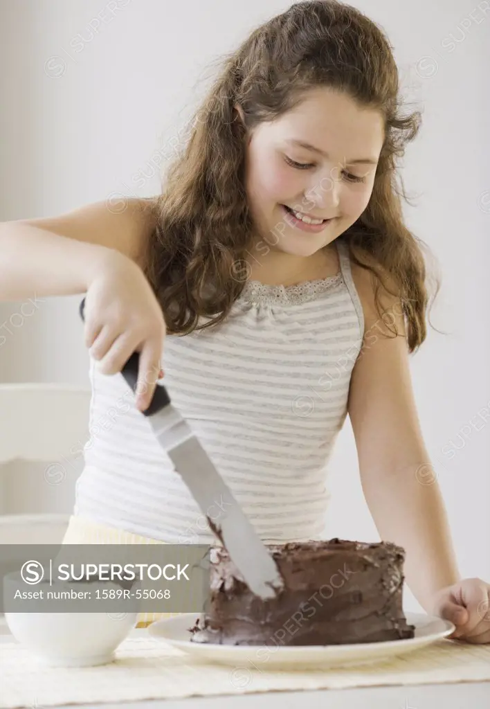 Hispanic girl icing cake