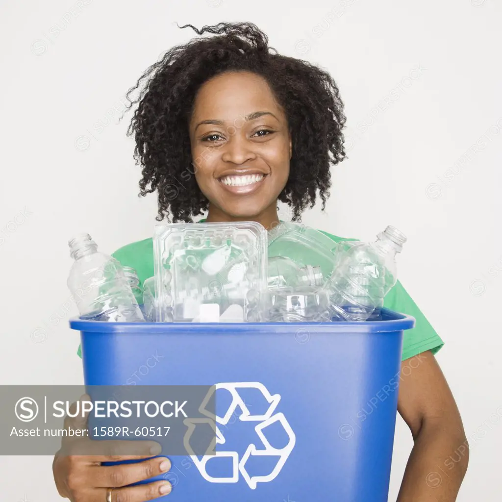 African woman holding recycling bin