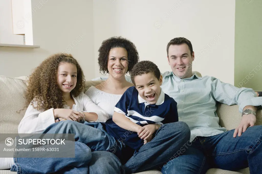 Mixed race family sitting on sofa and smiling