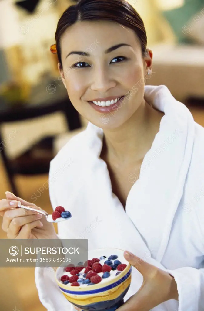 Asian woman eating yogurt with berries