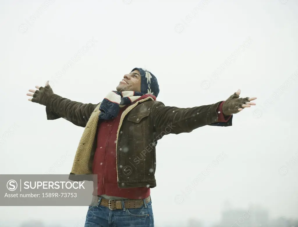 African American man standing in snow with arms outstretched