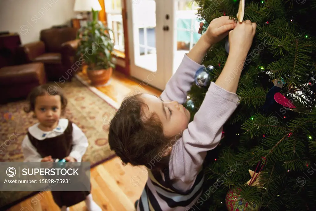 Mixed race girl decorating Christmas tree