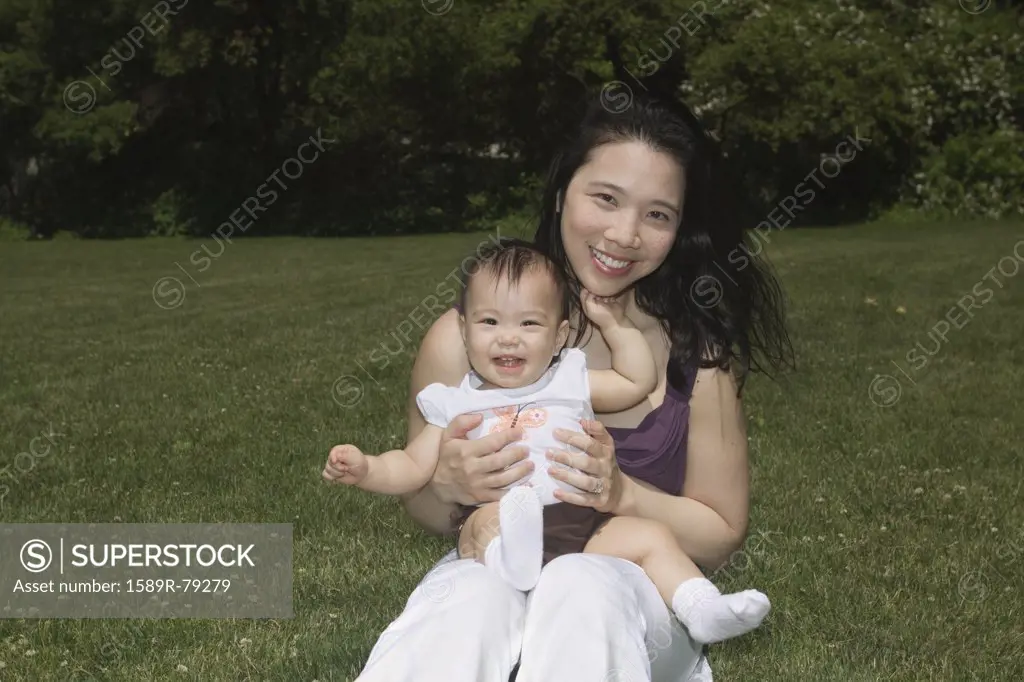 Chinese mother holding baby in park