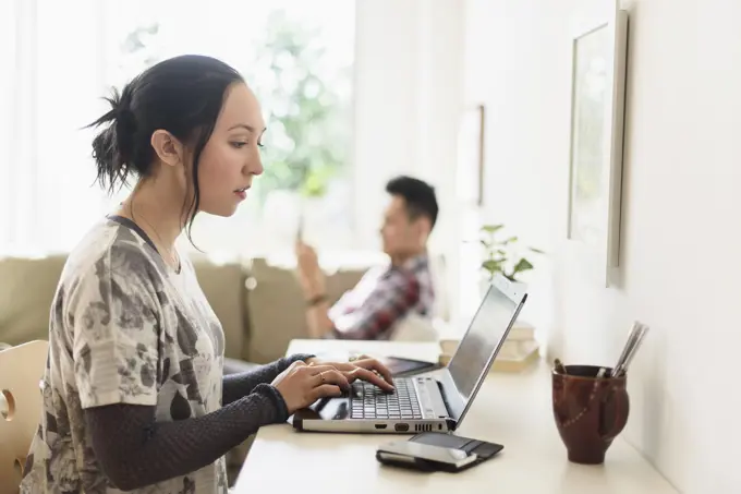 Woman using laptop at desk in living room