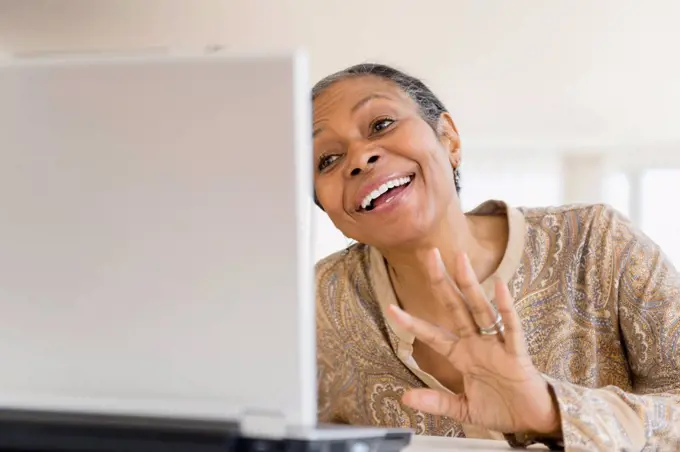 Mixed race woman using laptop at table