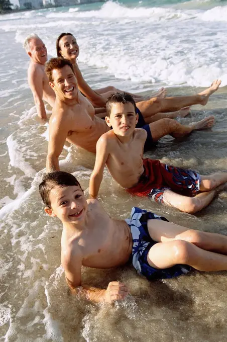 Family sitting in waves on beach