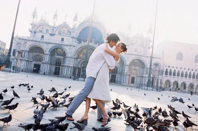 Couple surrounded by pigeons in St. Mark's Square, Venice, Veneto, Italy