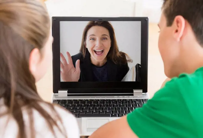 Caucasian children video conferencing with mother on laptop