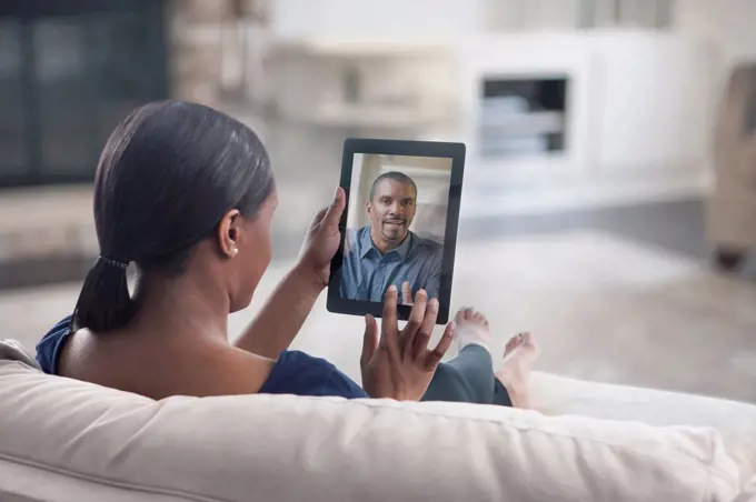 Woman video conferencing with father on digital tablet