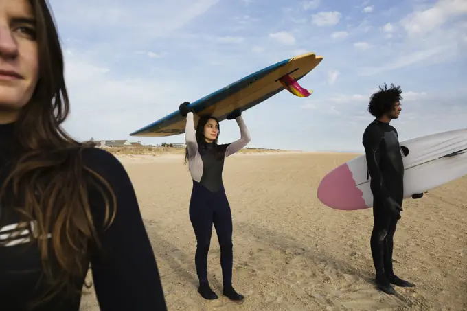 Surfers carrying boards on beach