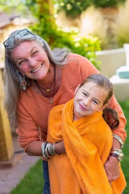 Caucasian grandmother wrapping granddaughter in towel in backyard