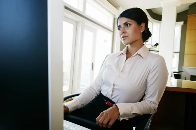 Mixed race businesswoman working at computer in office