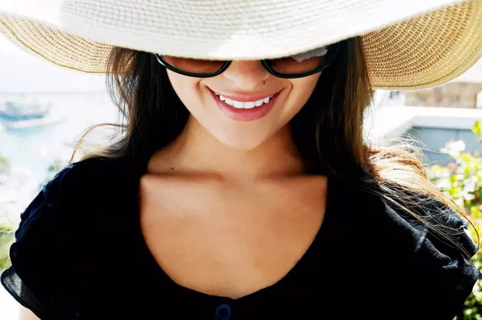 Smiling mixed race woman wearing sunglasses and sun hat