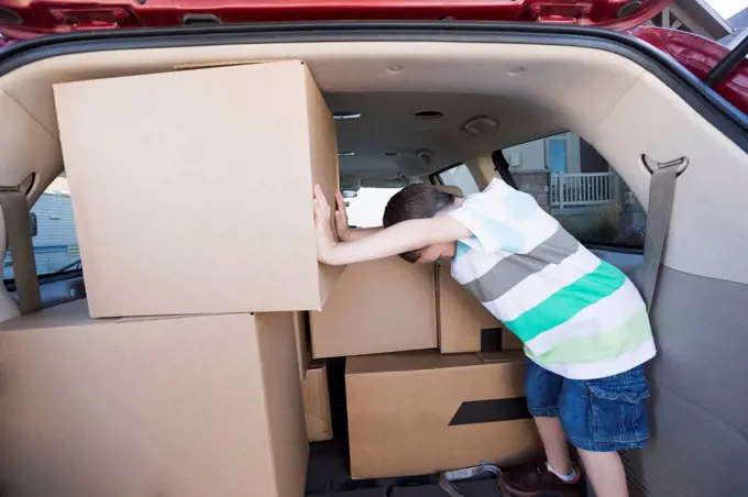 Caucasian boy packing cardboard boxes in car