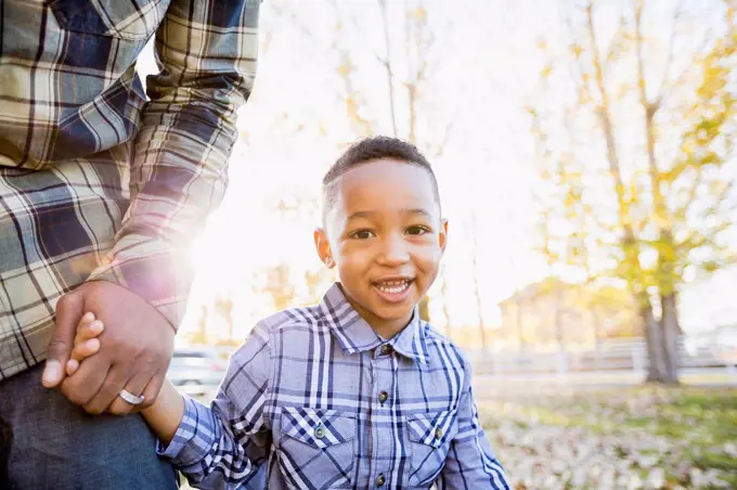 Black father and son walking in autumn leaves