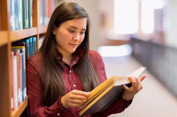 Mixed race student reading in library