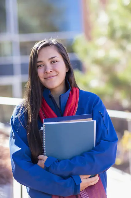 Mixed race student holding books on campus