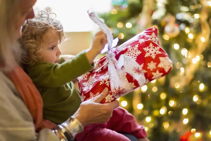 Caucasian grandmother and grandson opening presents near Christmas tree