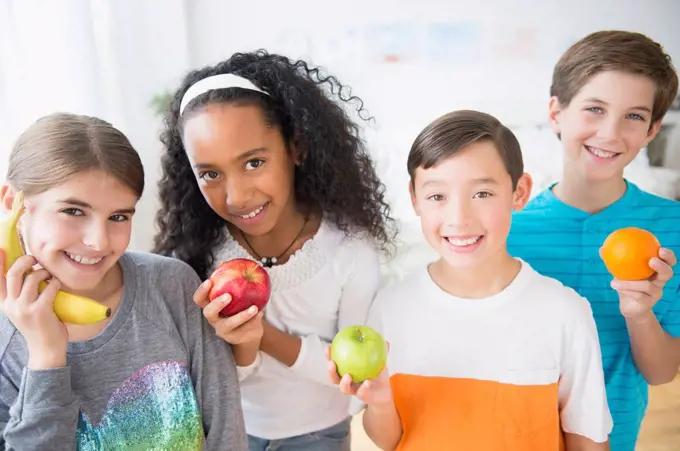 Smiling children playing with healthy fruit