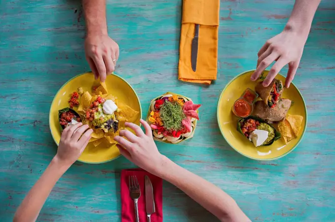 High angle view of hands reaching for food on plates