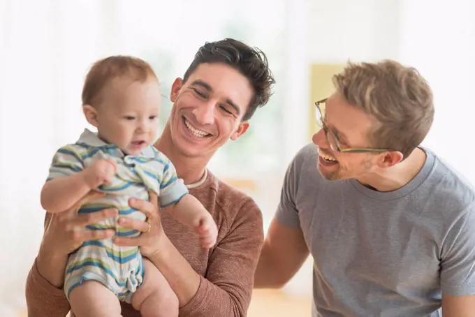 Caucasian gay fathers holding baby