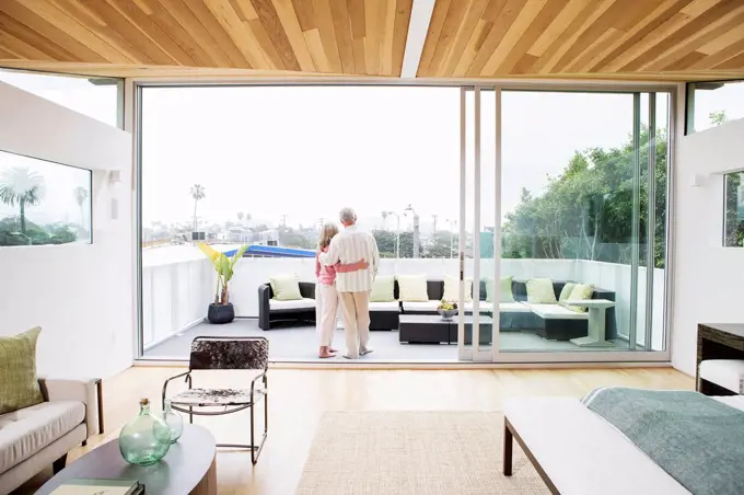 Older Caucasian couple hugging on porch