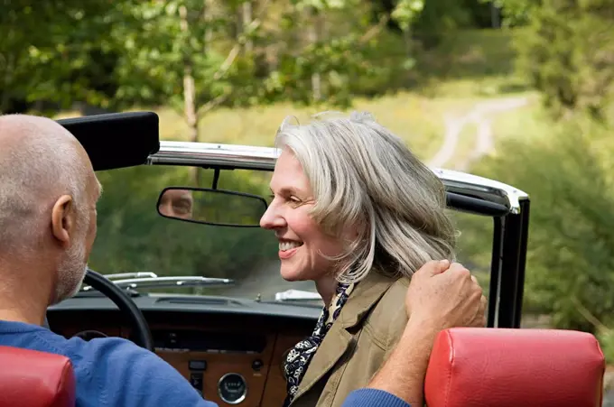 Rear view of older couple driving convertible