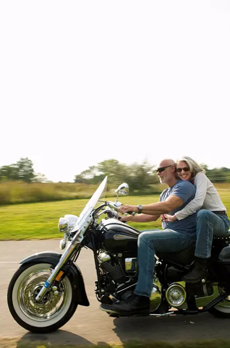 Older couple riding motorcycle on rural road