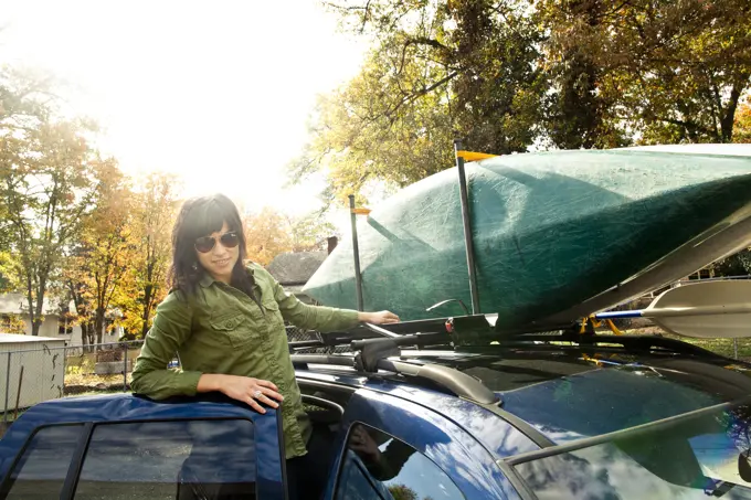 Caucasian woman packing kayak on car