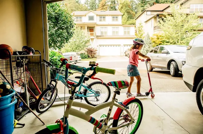 Mixed race girl playing with scooter