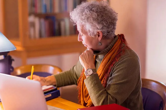 Older mixed race woman writing in library