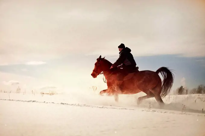 Caucasian man riding horse in snowy landscape