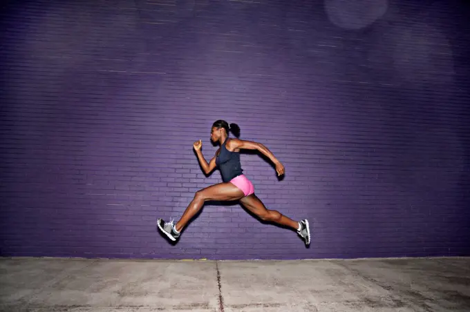 Female athlete running on sidewalk