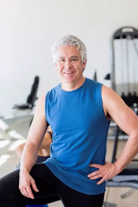 Older Hispanic man smiling in gym