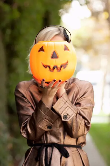 Caucasian woman holding jack o' lantern bucket