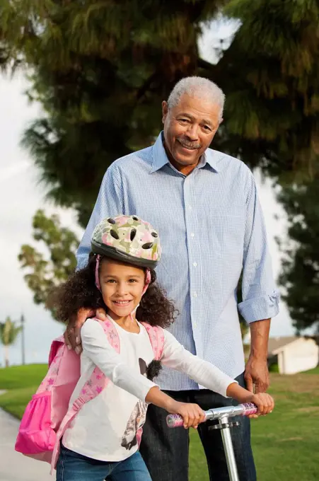 Man standing with granddaughter outdoors