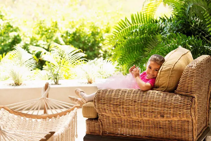 Hispanic girl sitting in armchair outdoors