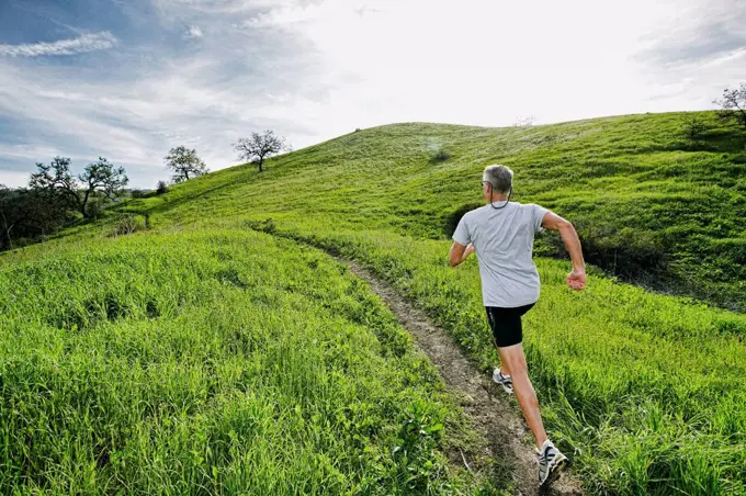 Older Caucasian man jogging on dirt path